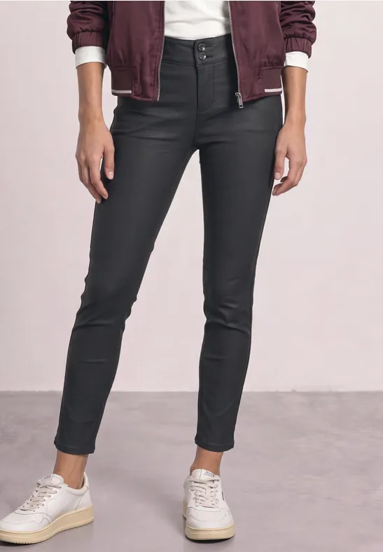 Schlanke schwarze beschichtete Jeans mit hohem Bund, legerem Umschlag am Knöchel und weißen Sneakers.