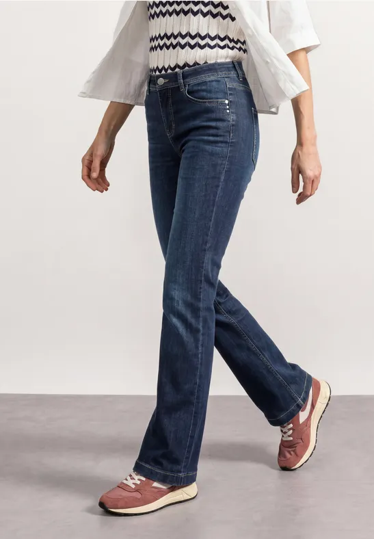 Personne en jean bleu et baskets rouge clair marche.