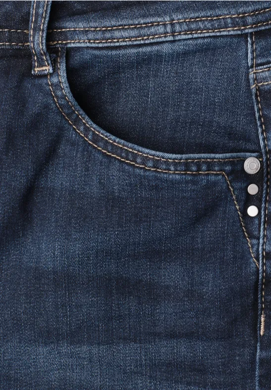 Gros plan d'un jean bleu foncé avec poche, passants, surpiqûres et rivets en métal.