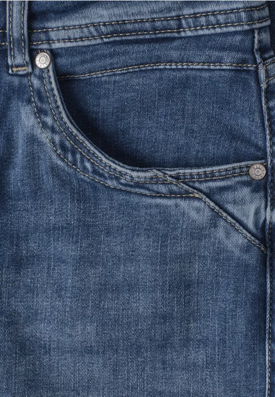 Gros plan sur l’avant d’un jean bleu, poche et coutures visibles.