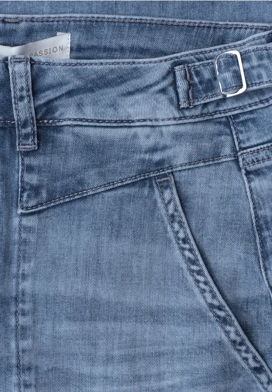 Gros plan sur jean bleu avec poche, ceinture et boucle latérale réglable.