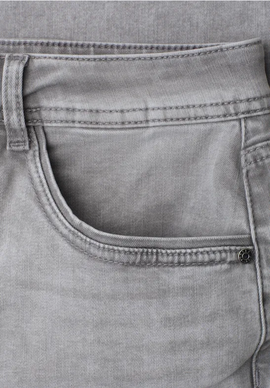 Gros plan d’un jean gris montrant la poche avant, les passants et les coutures.