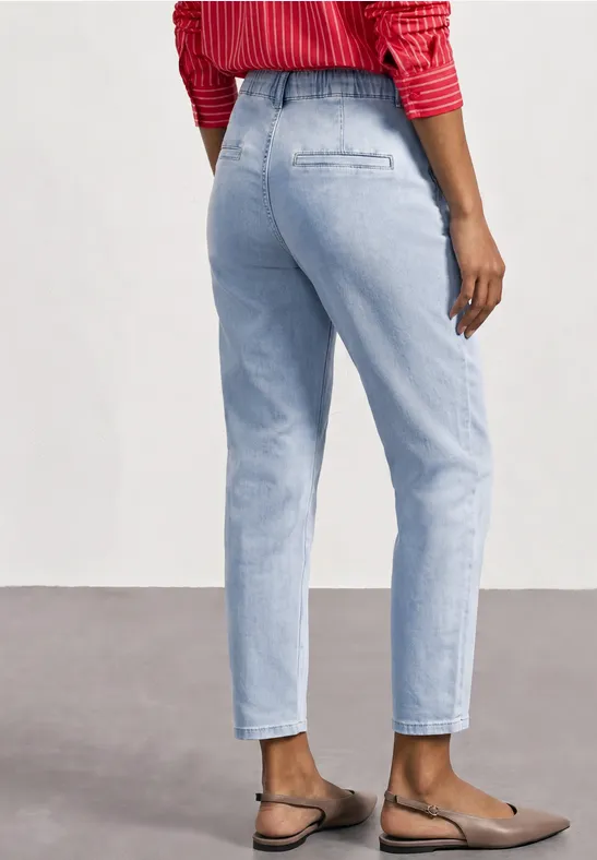 Frau von hinten in hellblauen Jeans, rotem gestreiften Oberteil und flachen Loafers.