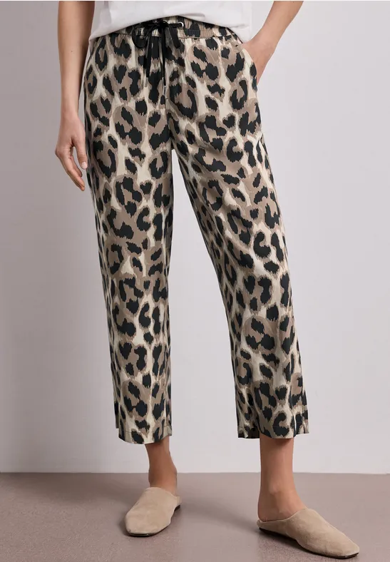 Pantalon droit à motif léopard ceinturé, porté avec des mules beiges.