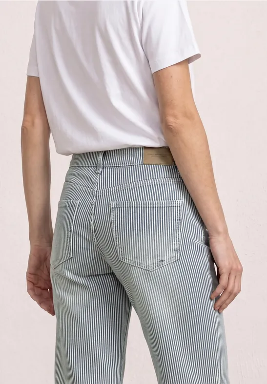 Personne vue de dos portant un t-shirt blanc et un jean bleu clair rayé.