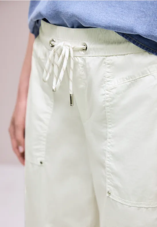 Pantalon clair et ample à cordon de serrage, poches plaquées, porté avec un t-shirt bleu.