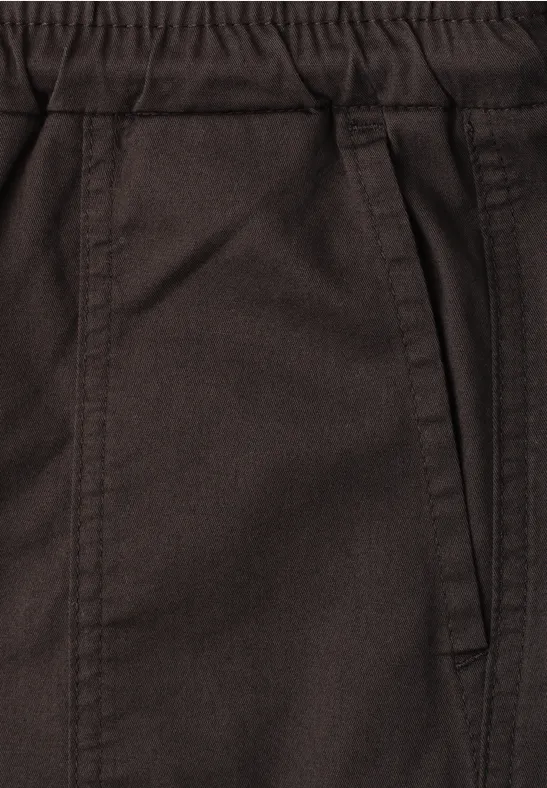 Close-up van een bruine broek met elastische tailleband en zijzak.