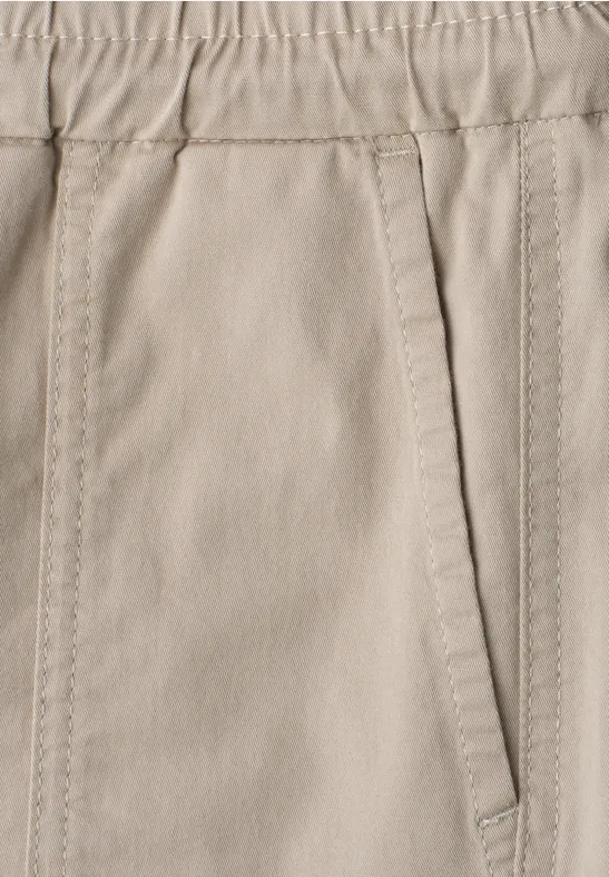 Close-up van een beige broek met elastische band en zijzak