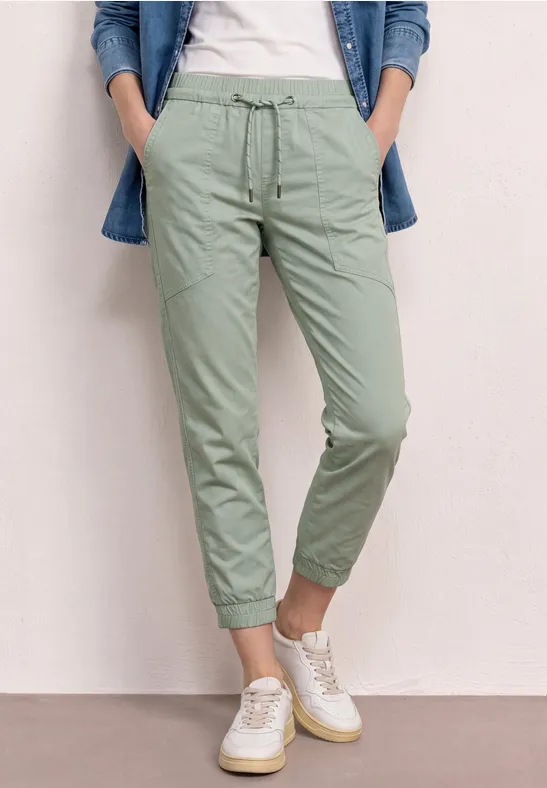 Persoon met lichtgroene chino en witte sneakers.