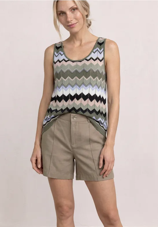 Femme en top sans manches à motif zigzag et short beige sur fond clair.