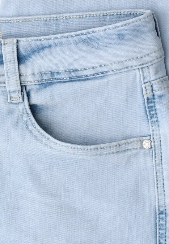 Close-up van een lichtblauwe spijkerbroek met voorzak en riemlussen.