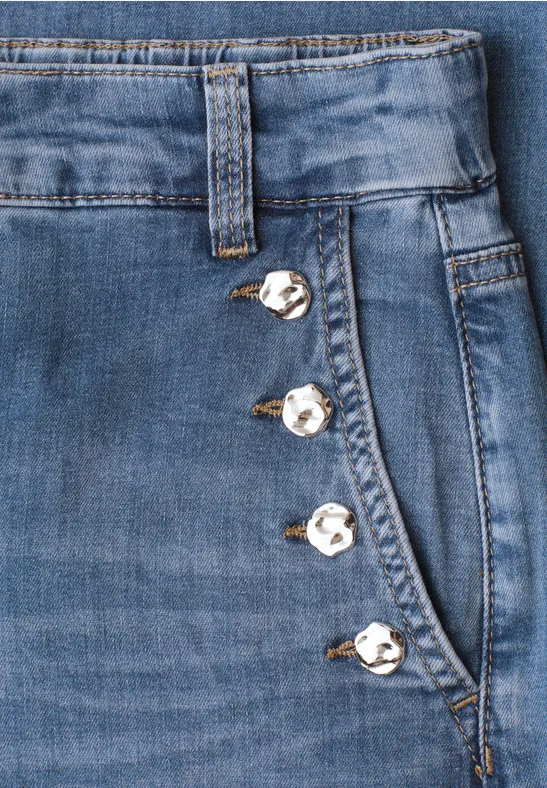 Jean bleu avec boutons décoratifs argentés alignés le long de la poche latérale