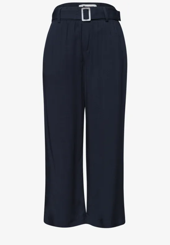 Dunkelblaue, weite Hose mit hohem Bund, eckiger Gürtelschnalle und eleganten Bügelfalten.