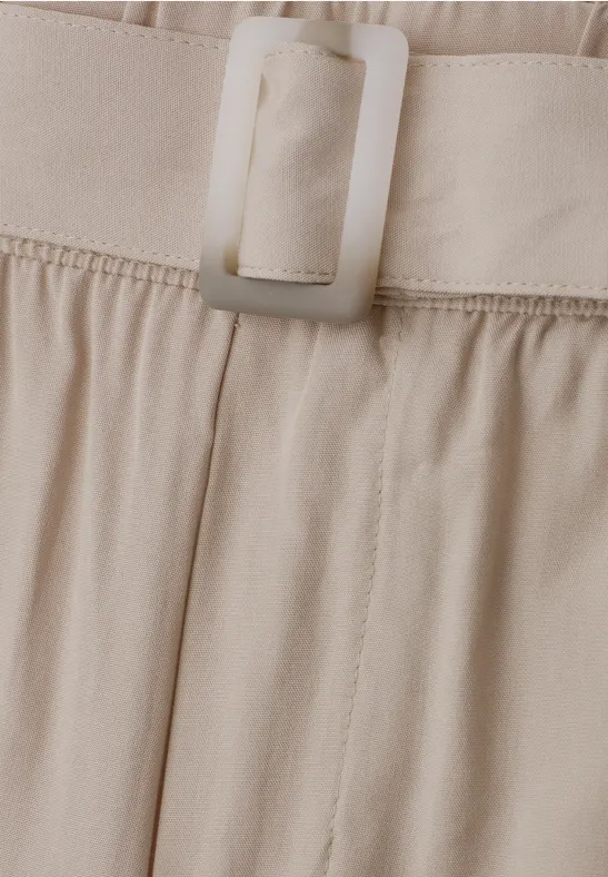Close-up van een beige stoffen riem met rechthoekige gesp aan een broek