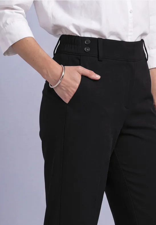 Schwarze Stoffhose mit Leistentasche, weißes Hemd und silbernes Armband.