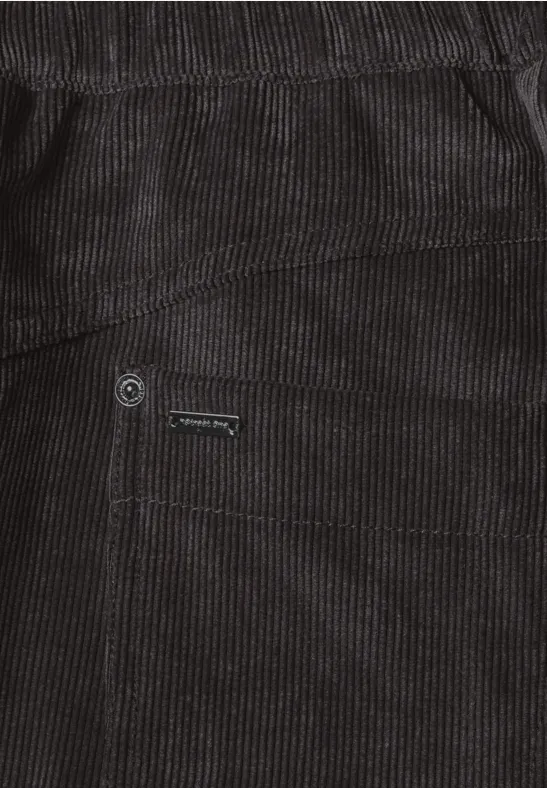 Close-up van een zwarte corduroy broek met zak en metalen knoop