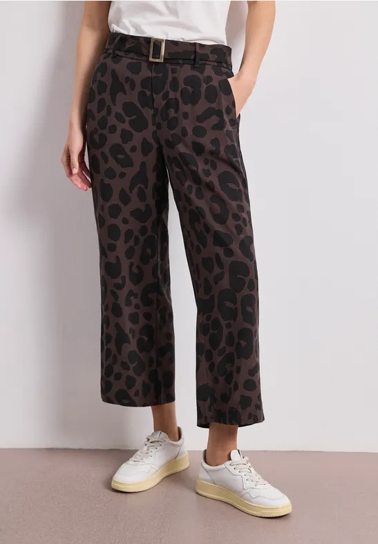 Damesbroek met wijde pijpen, hoog model en bruine-zwarte luipaardprint, inclusief riem en witte sneakers.