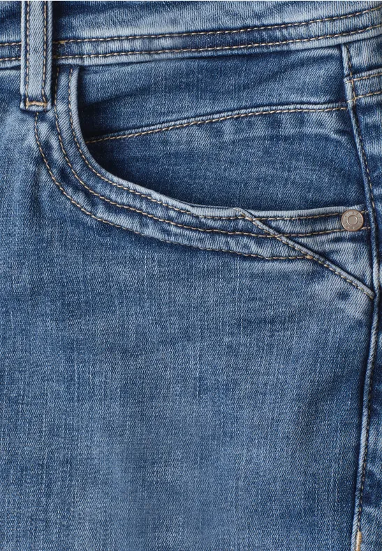 Gros plan sur une poche de jean bleu, avec couture et passant de ceinture visible