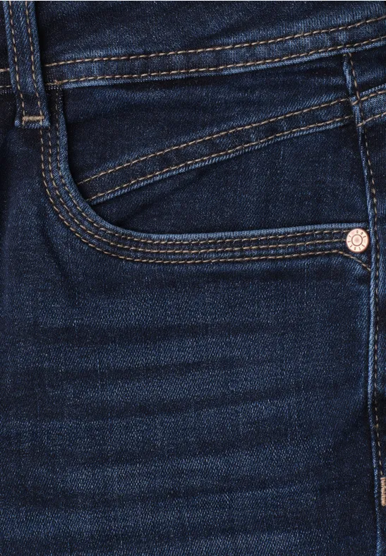 Gros plan d’un jean bleu foncé, poche et coutures apparentes.