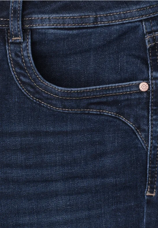 Nahaufnahme einer dunklen Jeanshose mit Gesäßtasche, Niete und sichtbaren Nähten.