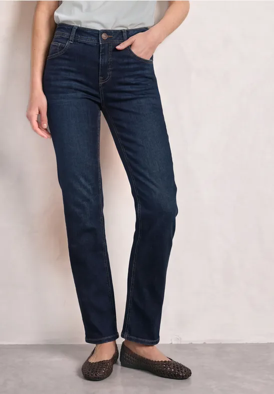 Une personne porte un jean bleu foncé droit et des ballerines noires.