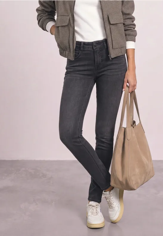 Personne porte un jean skinny noir, des baskets blanches, une veste bomber kaki, un t-shirt blanc et un sac beige.