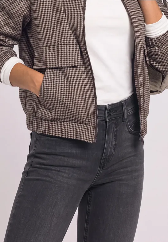 Buste d’une personne portant une veste à carreaux, un t-shirt blanc et un jean foncé.