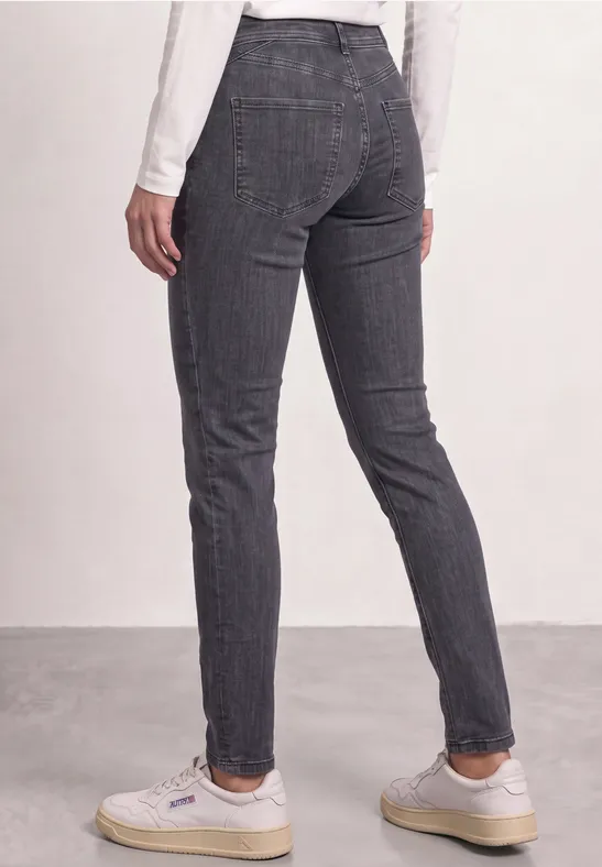 Vue arrière d’une personne portant un pantalon slim gris à carreaux et des baskets blanches.