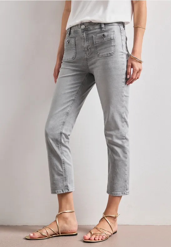 Lichtgrijze, korte damesjeans gecombineerd met verfijnde sandaaltjes met dunne bandjes.