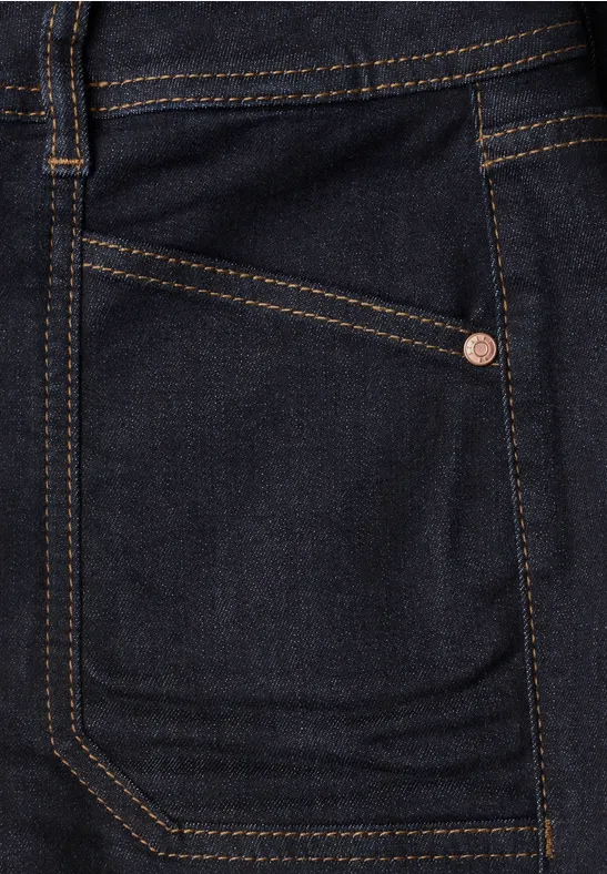 Poche d'un jean bleu foncé avec coutures contrastées orange et rivet métallique.
