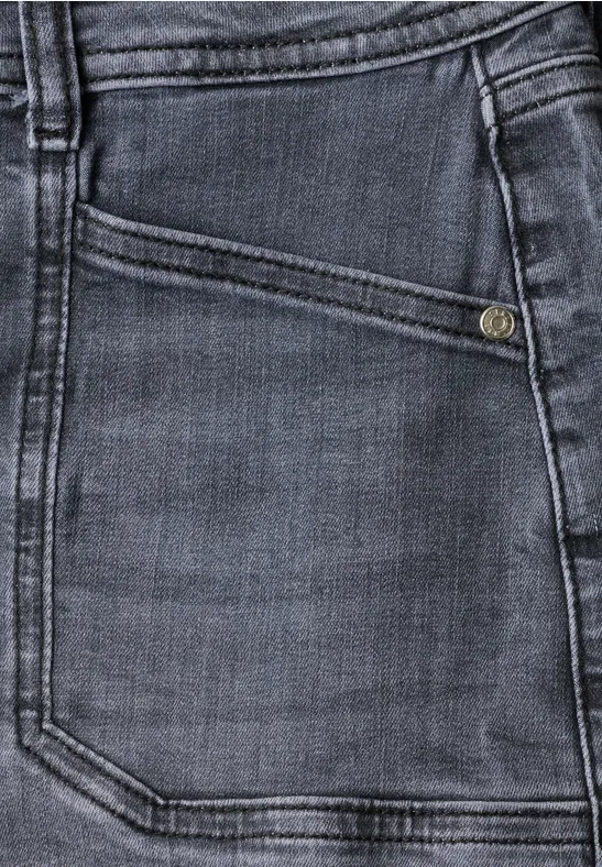 Gros plan d'une poche de jean gris foncé avec surpiqûres apparentes et bouton métallique.