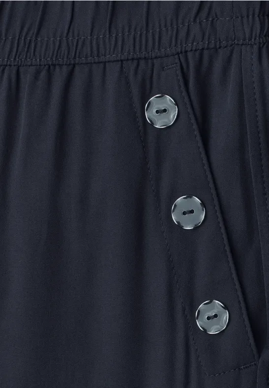 Donkerblauwe stof met elastische taille en drie zilverkleurige knopen op de zijzak.