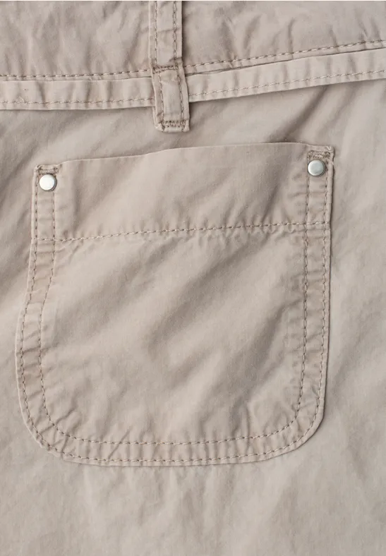 Close-up van een beige katoenen broek met een opgestikte zak.