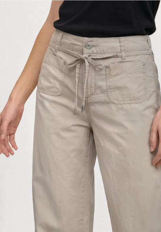 Lichtbeige damesbroek met wijde pijpen, trekkoord, zakken en knoop, gecombineerd met een zwart topje