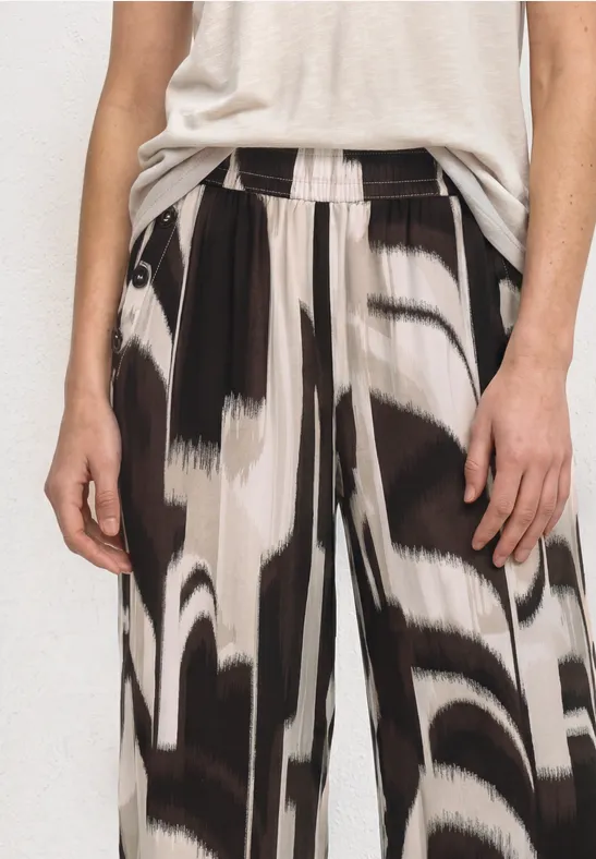 Een persoon draagt een wijdvallende broek met abstract zwart-witpatroon en een licht shirt.