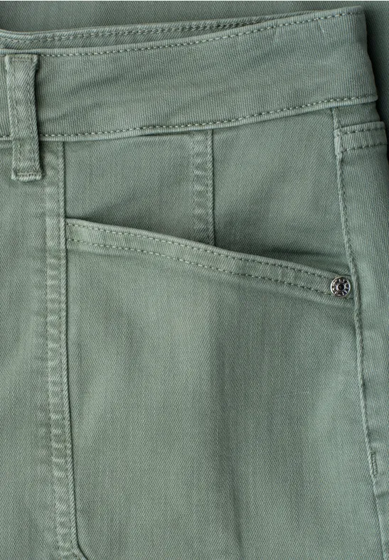 Gros plan sur une poche avant de pantalon vert, coutures visibles et passants pour ceinture.