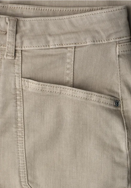 Gros plan sur un pantalon beige avec passants de ceinture et poches avant.