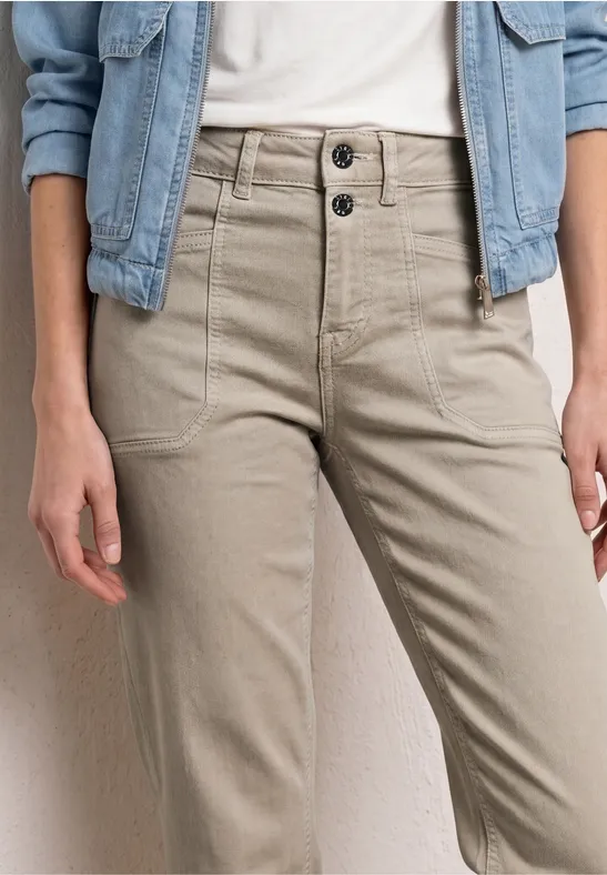 Personne porte une veste en jean claire, un t-shirt blanc et un pantalon beige taille haute avec boutons noirs.