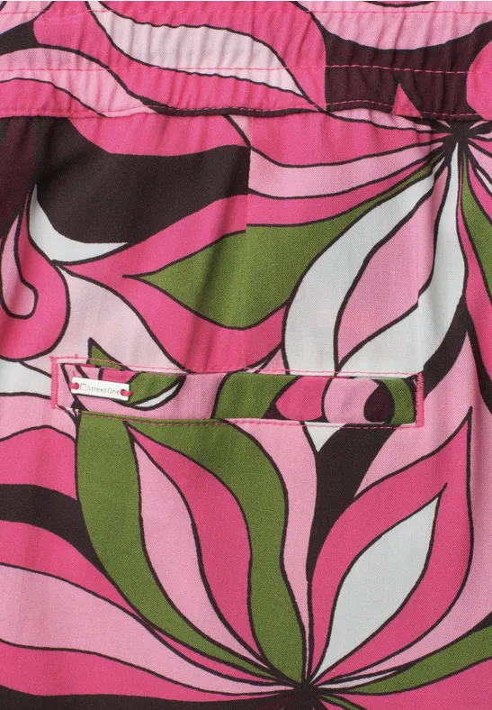Buntes, psychedelisches Blumenmuster in Pink, Grün, Weiß und Schwarz auf Stoff.