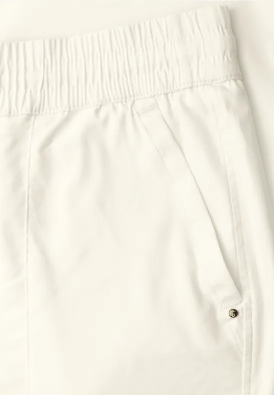 Nahaufnahme einer weißen Hose mit elastischem Bund und seitlicher Tasche mit Druckknopf.