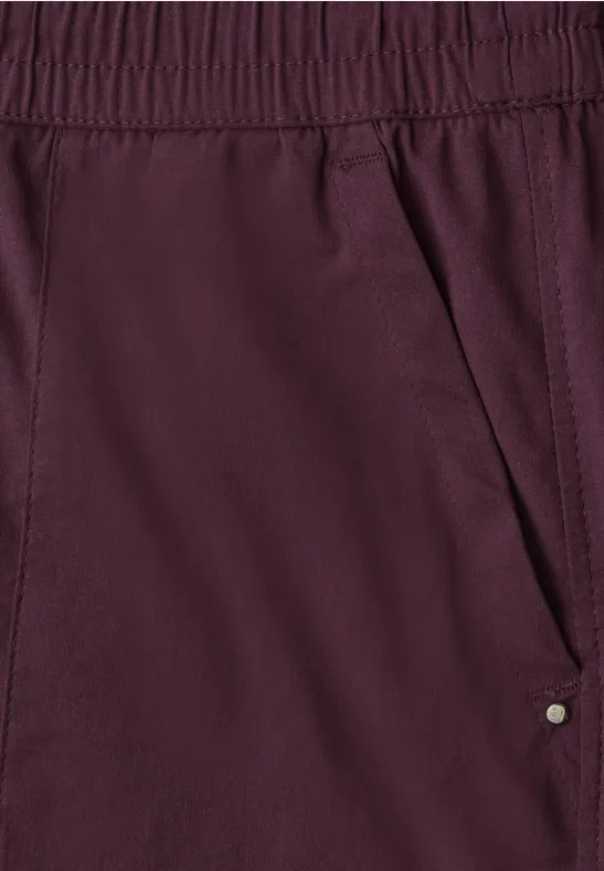 Nahaufnahme einer burgunderroten Stoffhose mit elastischem Bund und seitlicher Tasche