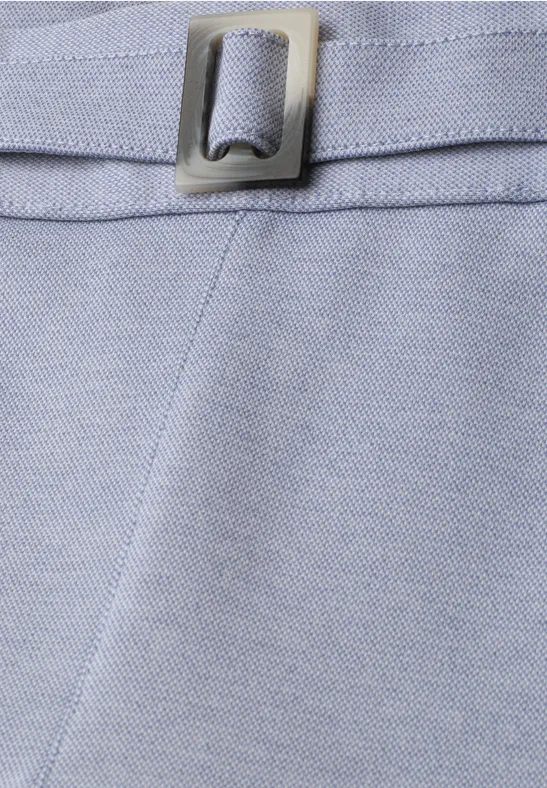 Gros plan sur un tissu bleu clair avec couture apparente et boucle métallique argentée.