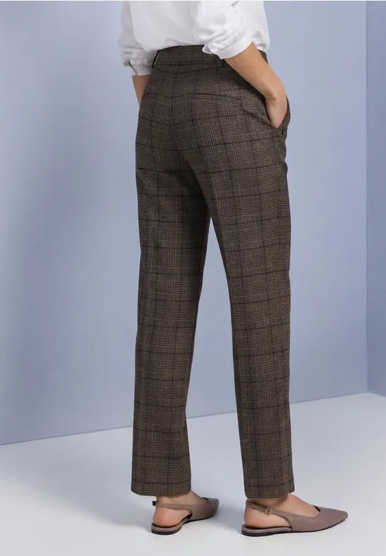 Vue de dos d’une personne portant un pantalon à carreaux brun, un haut blanc et des mocassins beiges.