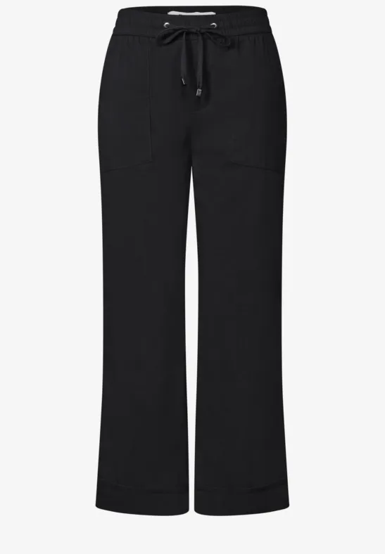 Schwarze, weite Hose mit elastischem Bund und Kordelzug, zwei aufgesetzte Taschen vorne.