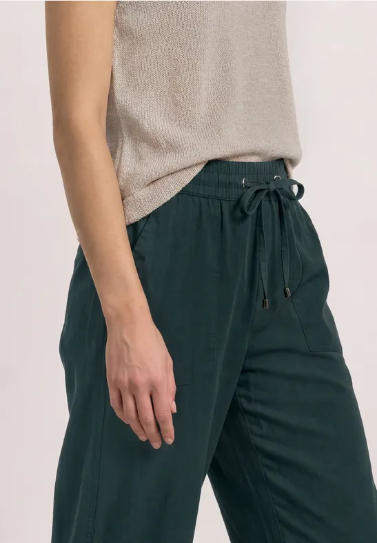 Personne porte un pantalon vert foncé en lin à taille élastiquée et coupe droite.