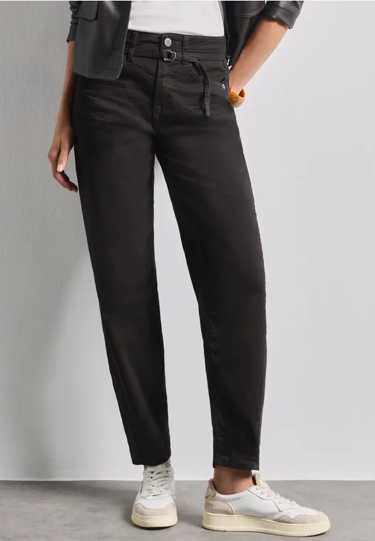 Jean noir taille haute et coupe décontractée porté avec des baskets blanches, pour un look casual chic.