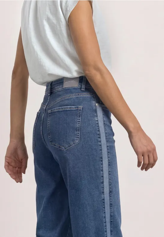 Profil einer Person in hoch taillierter Jeans und weißem T-Shirt