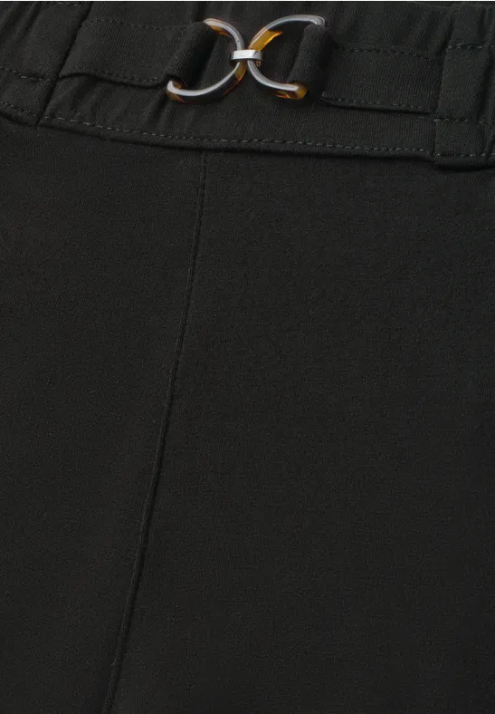 Zwarte broek met elastische taille en decoratieve gouden gespen.