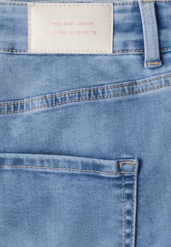 Gros plan sur un jean bleu clair avec poche arrière, passants de ceinture et étiquette cousue.