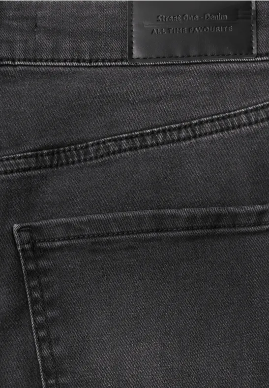 Gros plan d'un jean noir, poche arrière et étiquette visible à la taille